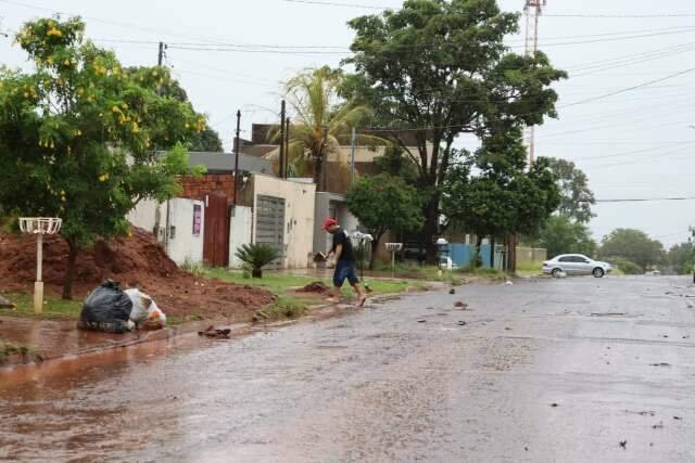 Morador limpa boca de lobo com enxada para evitar alagamento de casa