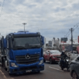 Caminhão-cegonha estaciona sobre a faixa amarela e tumultua trânsito