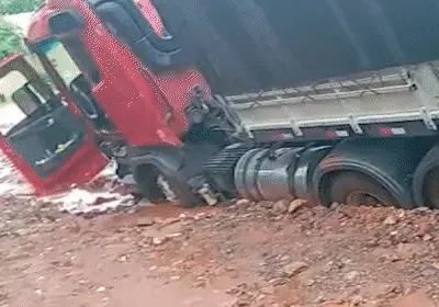 Carreta atola em vala durante chuva e precisa de retroescavadeira para socorrer