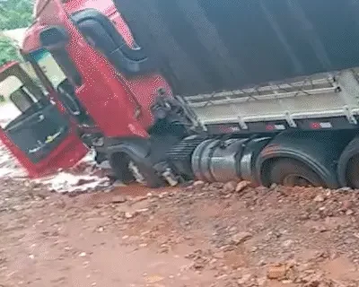 Carreta atola em vala durante chuva e precisa de retroescavadeira para socorrer