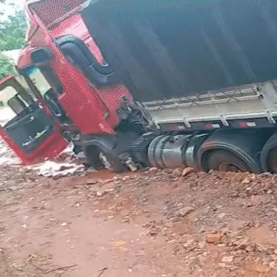 Carreta atola em vala durante chuva e precisa de retroescavadeira para socorrer